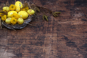 Osterhintergrund: Osternest mit gelben Ostereiern auf rustikalen Holz.	