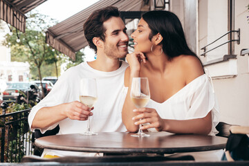 Smiling beautiful woman and her handsome boyfriend. Happy cheerful family. Sexy couple cheering with glasses of red wine at their date in restaurant. Drinking alcohol at veranda cafe