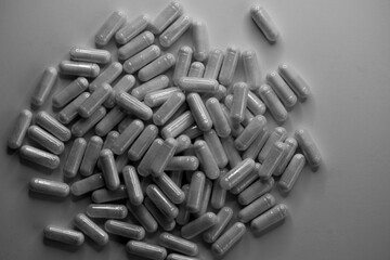 Heap of white pills on a white background, gray copy space