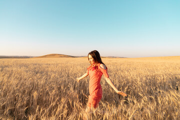 Young woman in the wheat field. Connecting with nature concept. Moments of joy. Arms out to the side. Copy space