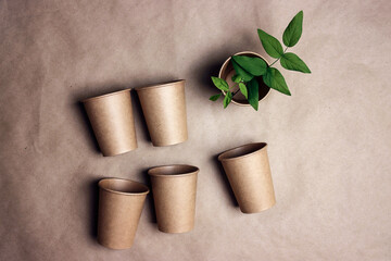 Set of eco-friendly coffee to go cups with green leaves on brown paper background.
