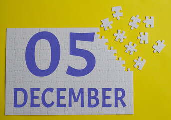 5 december calendar date on a white puzzle with separate details. Puzzle on a yellow background with a blue inscription