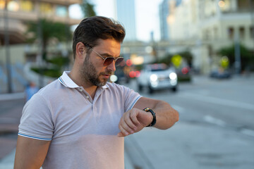 Stylish man wearing sunglasses and shirt. Handsome man outdoors portrait. Portrait of stylish male model outdoor. Fashion male posing near skyscraper on the street. Fashionable man in urban style.