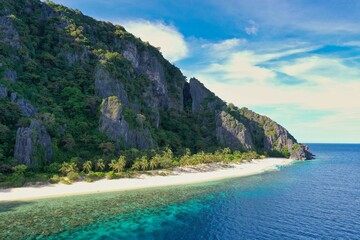 Obraz premium Panorama drone shot of the paradisiacal beach of Coron, Palawan in the Philippines with fine white beach, palm trees and majestic rocks.