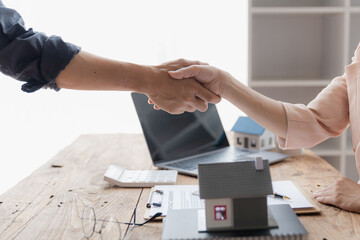 Real estate broker and customer shaking hands after signing a contract: real estate, home loan and insurance concept.