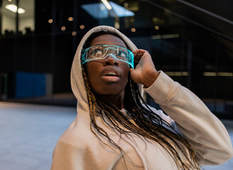 African woman wearing futuristic virtual reality goggles, plunged into a world of endless...