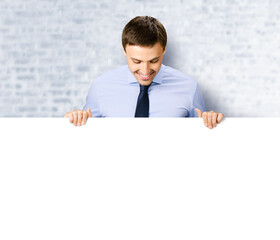 Portrait image of business man professional bank manager in confident cloth. Businessman stand behind hang over, look at empty white banner signboard with copy space. White bricks wall background