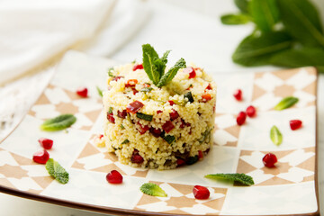 Couscous salad with pomegranate and mint leaves.