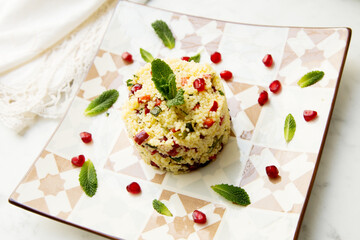 Couscous salad with pomegranate and mint leaves.