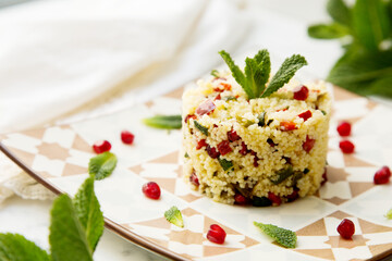 Couscous salad with pomegranate and mint leaves.
