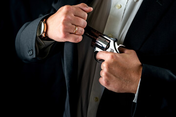 man in a suit holding a gun as a criminal isolated on a black background.