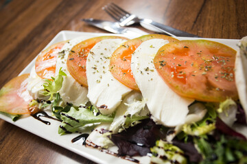 Caprese salad is an Italian salad made up of sliced tomatoes and fresh mozzarella, and fresh basil leaves.