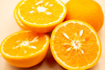 Oranges on pink background. One orange is cut in half, the other is whole.
