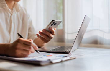 Close up of young man using calculator and laptop for doing financial mathematics on wooden table in office and working background - business, tax, accounting, statistics and analytical research conce