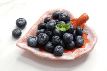 Fresh blueberries with mint leaves. The fruits are actual berries with many tiny seeds and are deep indigo to black color when ripe. Copy space.
