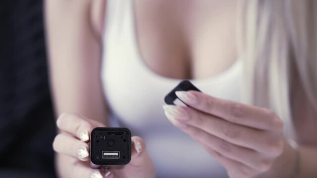 Woman shows a spy camera that looks like a cell phone charger cube. She shows how it works.