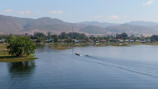 Traditional long boat approaching Taw Mwe Khaung Pagoda near Moebyel Lake, Myanmar. Aerial view