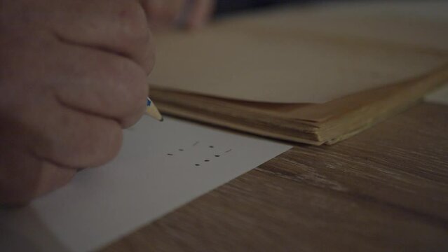 Man writing noting morse code on a  sheet of paper from an old book 4K