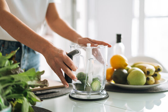 Young Slim Woman In White T-shirt And Blue Jeans Cooking Green Smoothie Healthy Food In Kitchen At Home