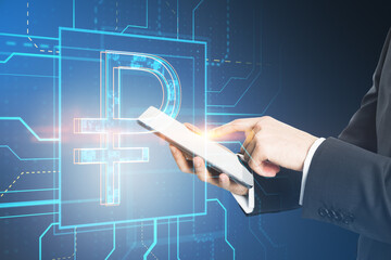 Close up of businessman hand pointing at mobile phone with glowing linear ruble hologram on blurry blue background. Investment, trade and finance concept. Double exposure.