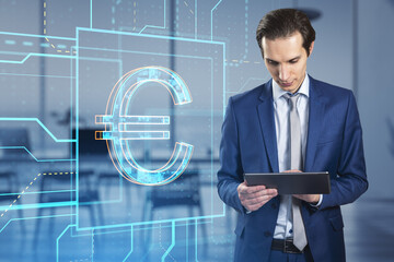Attractive young european businessman with tablet and glowing linear euro hologram standing on blurry office interior background. Investment, trade and finance concept. Double exposure.