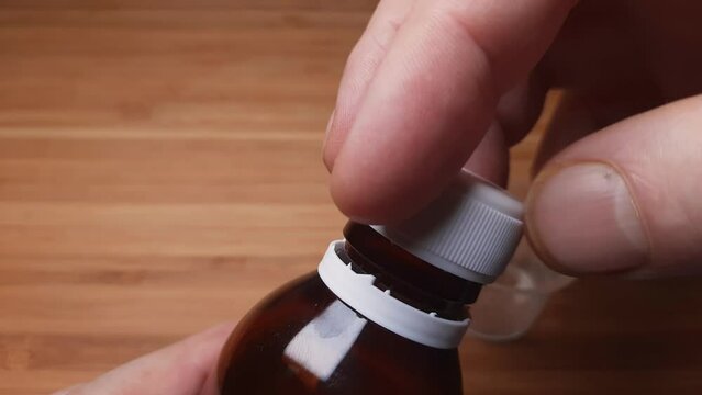 Unscrewing the lid of glass bottle of liquid medicines