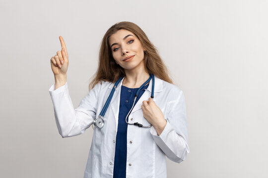 Portrait of a doctor's woman in a white coat who points up with her finger. Advertising poster, mockup. Medical services