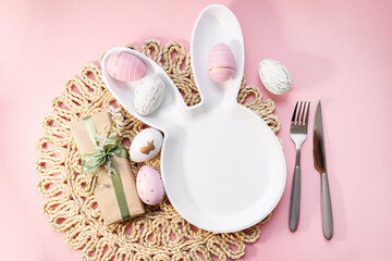 bunny plate with cutlery , easter eggs, gifts with green ribbon, spring sakura flowers on a pastel...