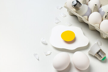 Eggs and bulbs on white background, space for text