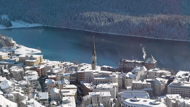 Detail view of the snow covered town of St. Moritz, Switzerland a lake and trees on a sunny winter day.