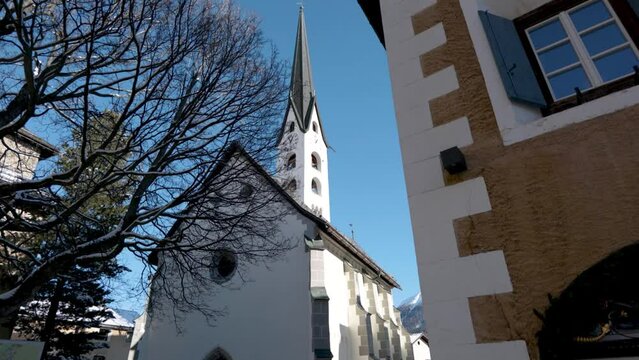 View of a traditional Swiss village church on a sunny winter day in Zuoz, Switzerland.