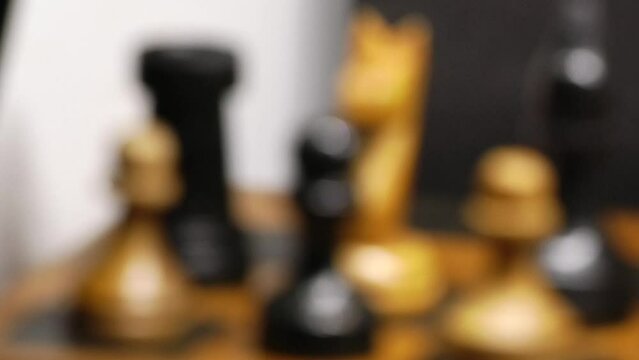 Some black and white wooden chess pieces on a chessboard in a very close up video	
