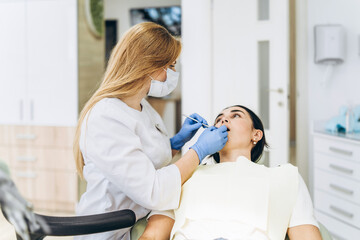 Female dentist with female patient in dental chair providing oral cavity treatment