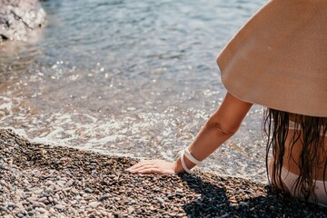 Woman travel sea. Happy tourist in hat enjoy taking picture outdoors for memories. Woman traveler posing on the beach at sea surrounded by volcanic mountains, sharing travel adventure journey