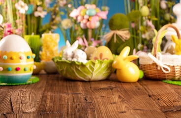 Obraz na płótnie Canvas Easter theme. Easter decorations. Easter eggs in basket and easter bunny. Bouquet of spring flowers. Rustic brown table and blue background.