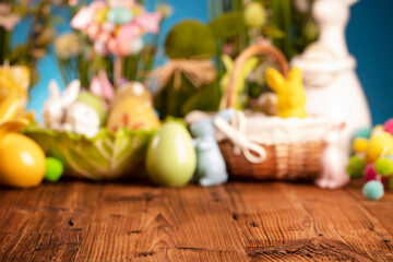 Easter theme. Easter decorations. Easter eggs in basket and easter bunny. Bouquet of spring flowers. Rustic brown table and blue background.