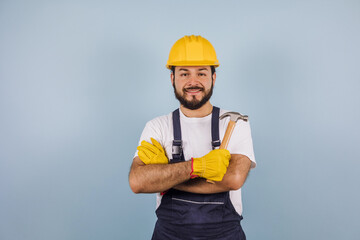 portrait of Hispanic bearded young man engineering and worker with hard helmet in Mexico Latin America on blue background	