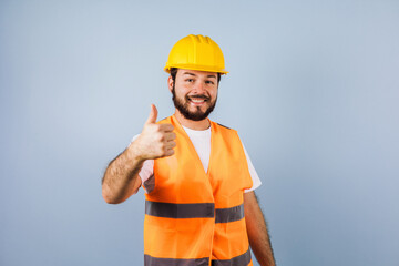 latin bearded young man and Professional worker with hard helmet and pointing finger in Mexico Latin America on yellow background