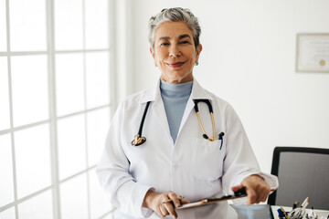 Female doctor with experience looking at the camera while standing in her office