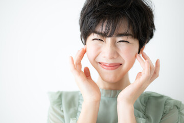 美容に使いやすい顔に手を添え笑顔が美しい日本人女性　コピースペース