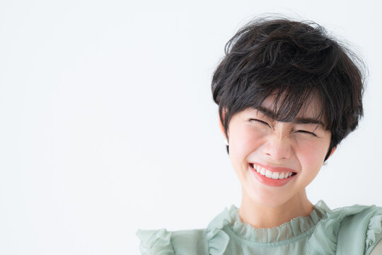 美容に使いやすい顔に手を添え笑顔が美しい日本人女性　コピースペース　