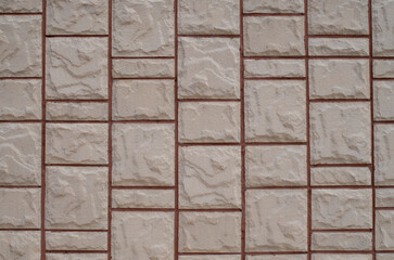 White cladding tiles imitating stone with red joints on wall close