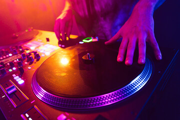 Close up of DJ hands on dj console mixer during concert in the club