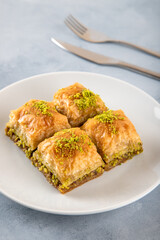 Pistachio Turkish baklava on a white plate.Close-up of four slices of baklava
