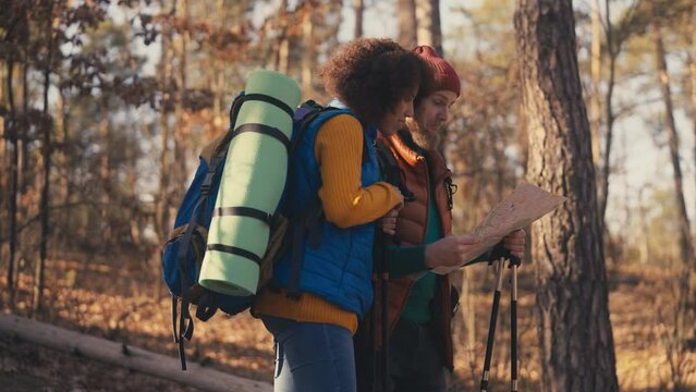Young man and his girlfriend looking for directions on map while hiking, trip