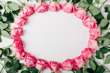Frame of fresh pink roses in full bloom on white background. Bunch of flowers with negative space for text. Top view, flat lay. Valentine's day or Mother's day card.