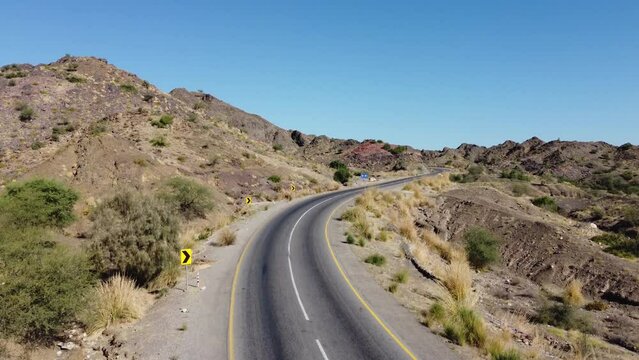 Aerial View Of Empty RCD Road Through Balochistan Snaking Through The Rocky Desert Landscape. Ascending Shot