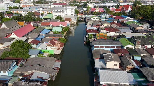 Aerial View Flying Along Khlong Bangkok Yai Canel Waterways. Dolly Back With Pan Up To Reveal Skyline