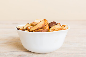 Fresh healthy Brazil nuts in bowl on colored table background. Top view Healthy eating bertholletia concept. Super foods