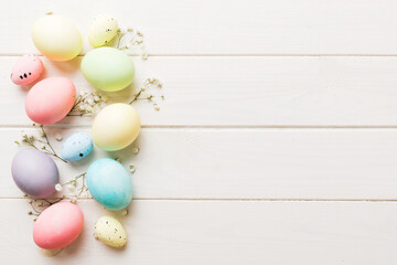 Happy Easter composition. Easter eggs on colored table with gypsophila. Natural dyed colorful eggs background top view with copy space